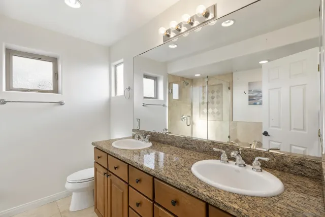 a bathroom with a granite countertop sink a toilet and a mirror