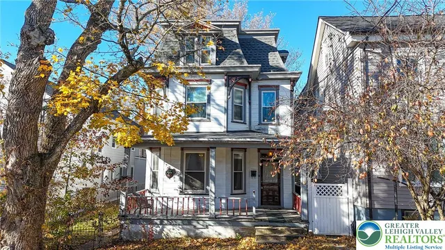 a view of a house with a tree and wooden fence