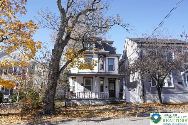 a front view of a house with a tree