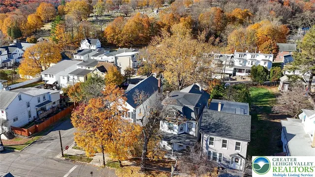 a view of a house with a small yard and large tree