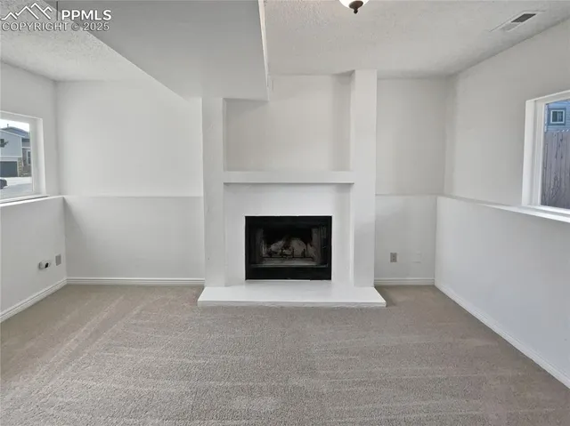 a view of an empty room with a fireplace and a window