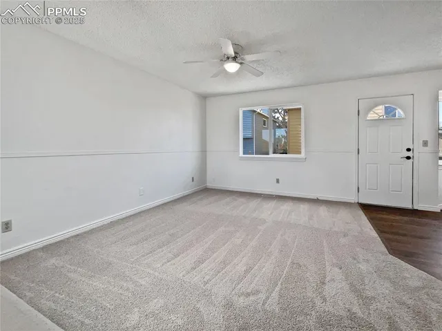 an empty room with wooden floor chandelier fan and windows