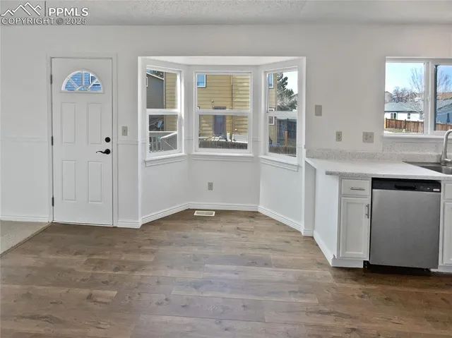a view of an empty room with window and wooden floor