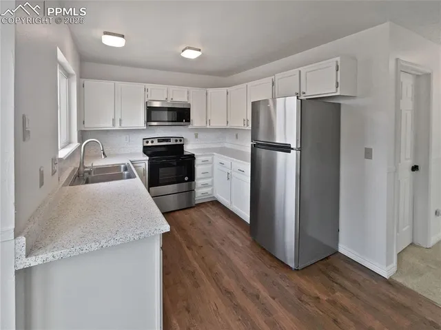 a kitchen with granite countertop a refrigerator stove and microwave