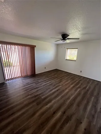 an empty room with wooden floor chandelier and windows