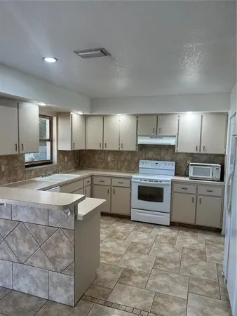 a large kitchen with a stove a sink dishwasher a refrigerator and a oven