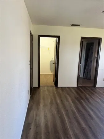a view of a hallway with wooden floor and a bathroom