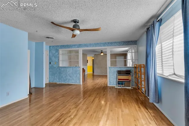 a view of a room with wooden floor and a ceiling fan