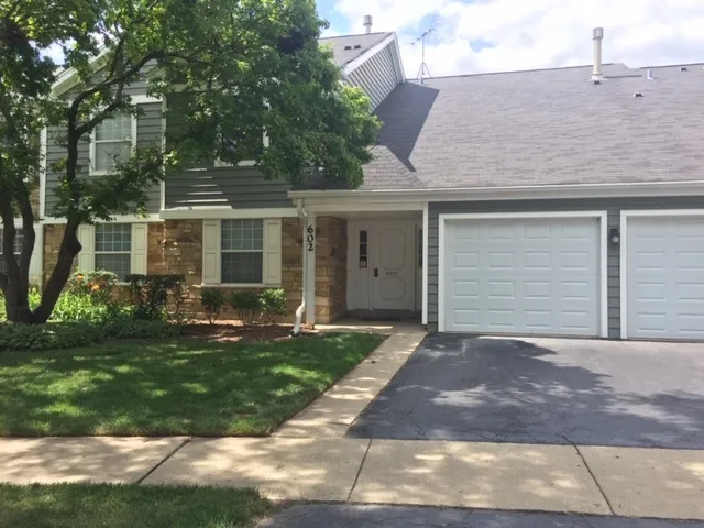 a front view of a house with a yard and potted plants