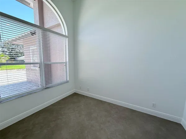 an empty room with chandelier fan and windows