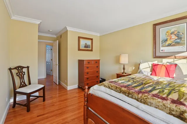 a bedroom with a bed a chair and painting on the wall