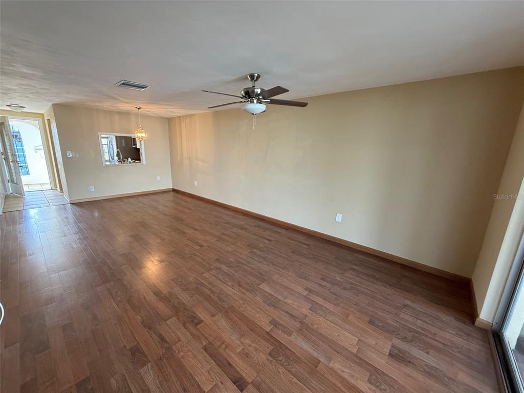 4233 Tamargo Drive, Unit 4233 New Port Richey, FL 34652 - Photo 3 of 13 an empty room with wooden floor ceiling fan and windows