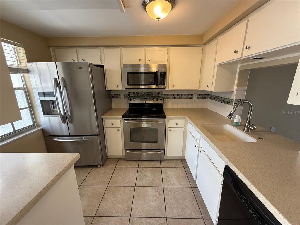 4233 Tamargo Drive, Unit 4233 New Port Richey, FL 34652 - Photo 4 of 13 a kitchen with a sink a microwave a refrigerator and cabinets
