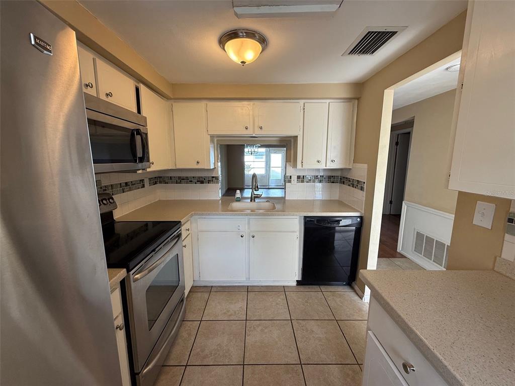 4233 Tamargo Drive, Unit 4233 New Port Richey, FL 34652 - Photo 5 of 13 a kitchen with a stove a sink and a microwave