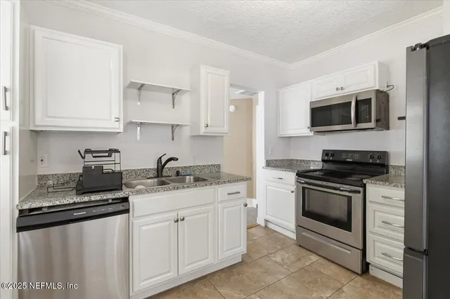 a kitchen with stainless steel appliances granite countertop white cabinets a stove a sink and dishwasher