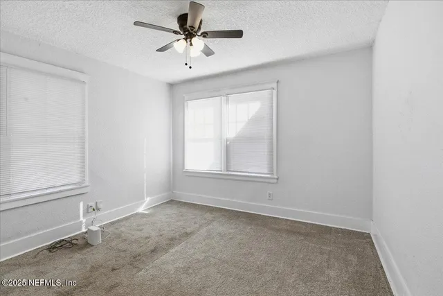 an empty room with a window and a fan