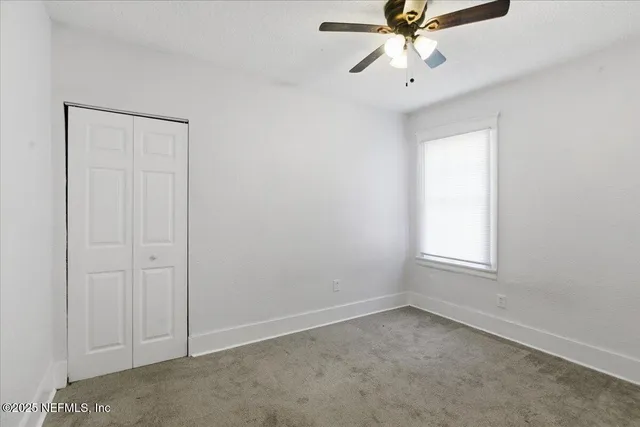 an empty room with fan and windows