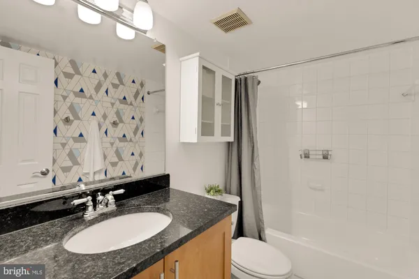 a bathroom with a granite countertop sink toilet a mirror a vanity and shower