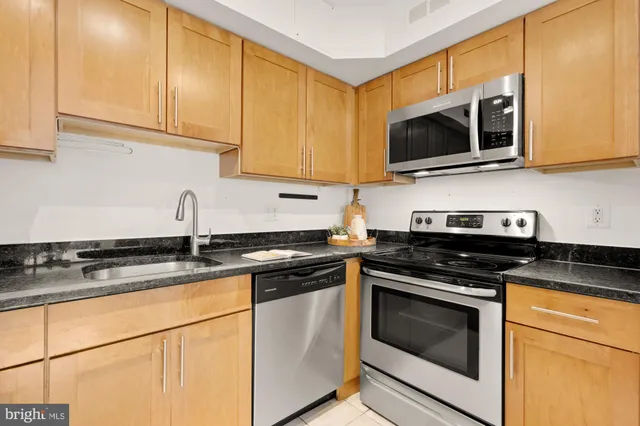 a kitchen with granite countertop white cabinets stainless steel appliances and a sink