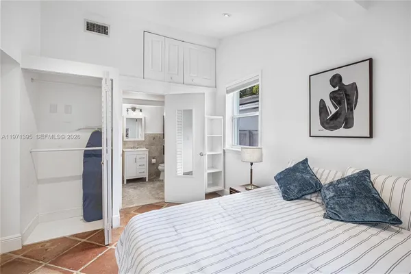 a bedroom with a bed and a refrigerator