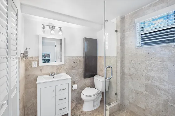 a bathroom with a toilet sink vanity granite and shower