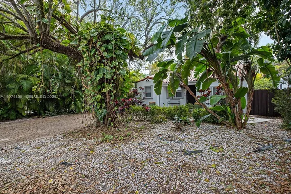 a backyard of a house with plants and large trees