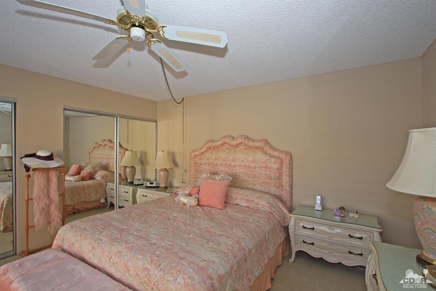 27 La Ronda Drive Rancho Mirage, CA 92270 - Photo 22 of 30 a bedroom with a bed and a chandelier