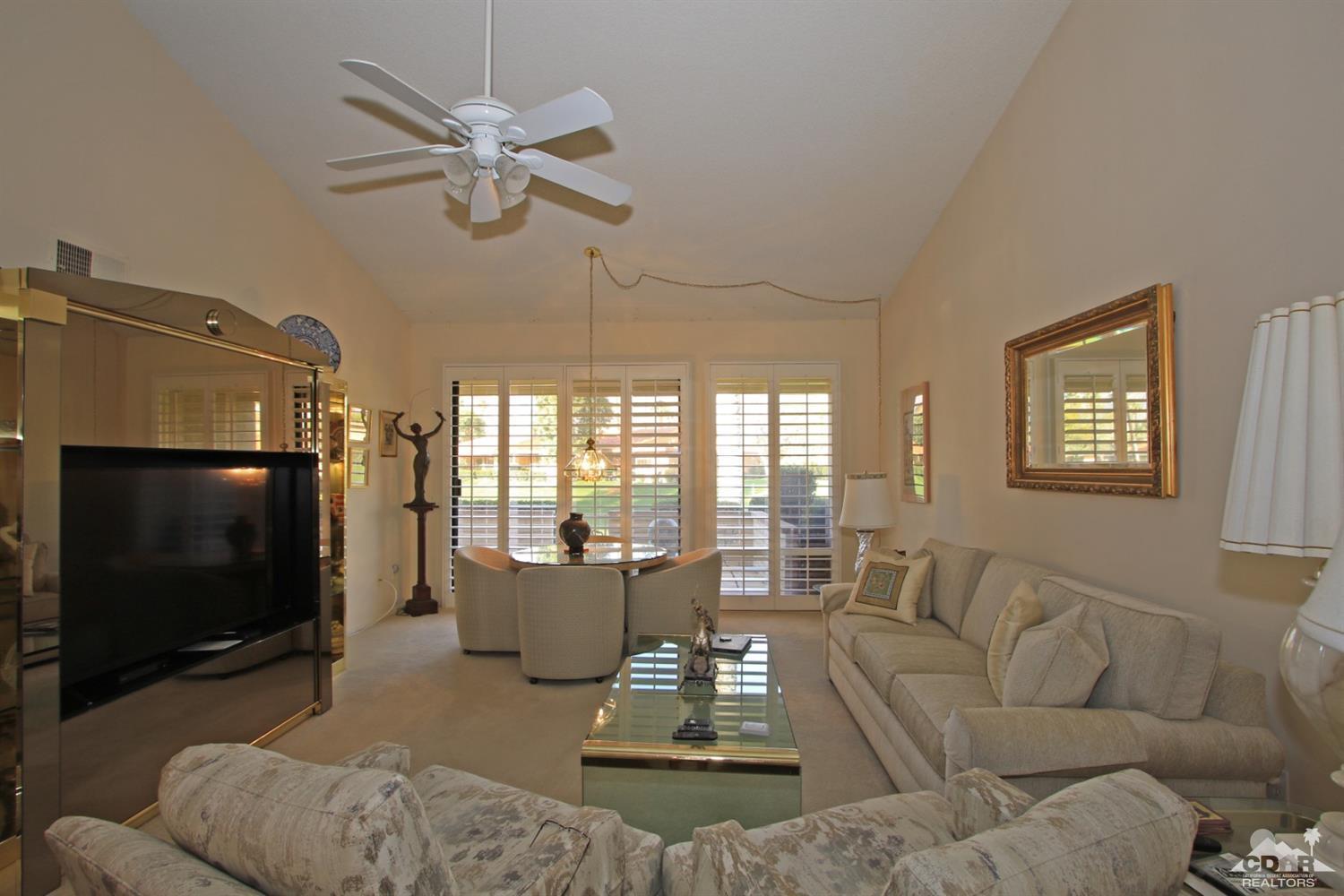 27 La Ronda Drive Rancho Mirage, CA 92270 - Photo 8 of 30 a living room with furniture a flat screen tv and a large window