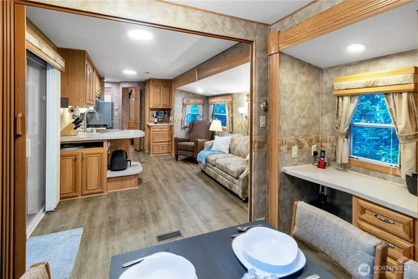 a living room with stainless steel appliances furniture a rug and a large window
