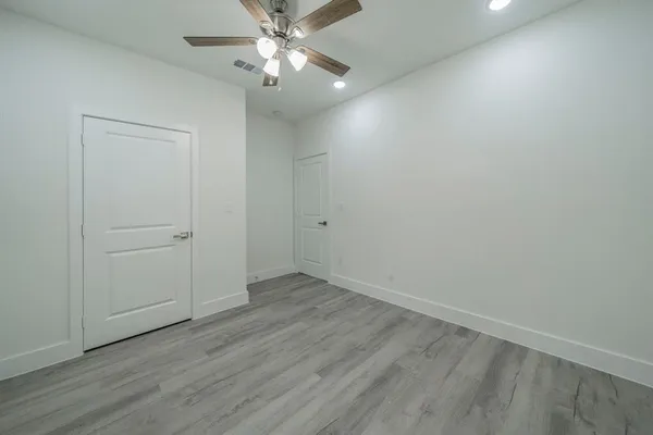 an empty room with wooden floor closet and fan