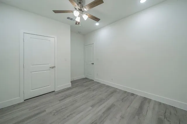 an empty room with wooden floor closet and fan