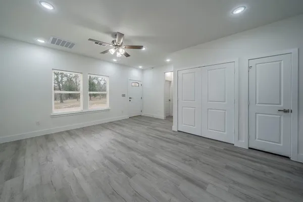a view of an empty room with a window and wooden floor