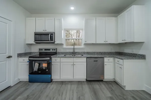 a kitchen with stainless steel appliances granite countertop a stove a sink and white cabinets