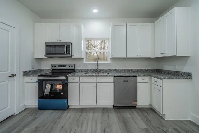 a kitchen with stainless steel appliances granite countertop a stove a sink and white cabinets