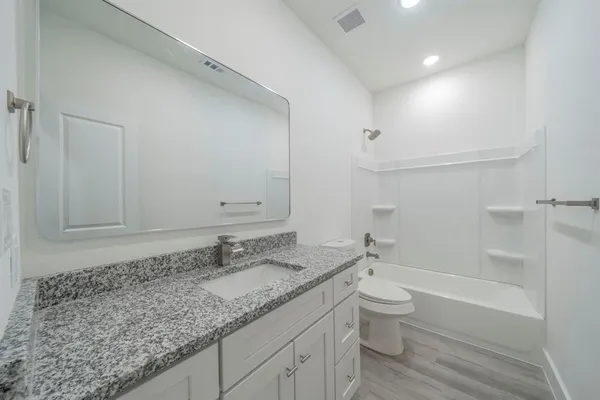 a bathroom with a granite countertop sink a toilet and shower