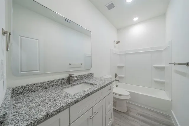 a bathroom with a granite countertop sink a toilet and shower