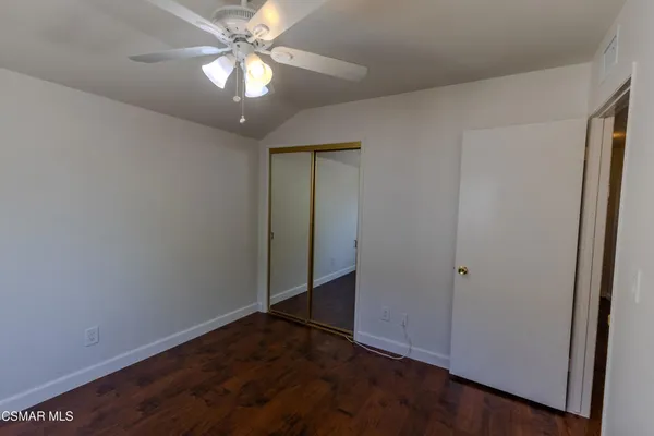 an empty room with closet and a chandelier fan