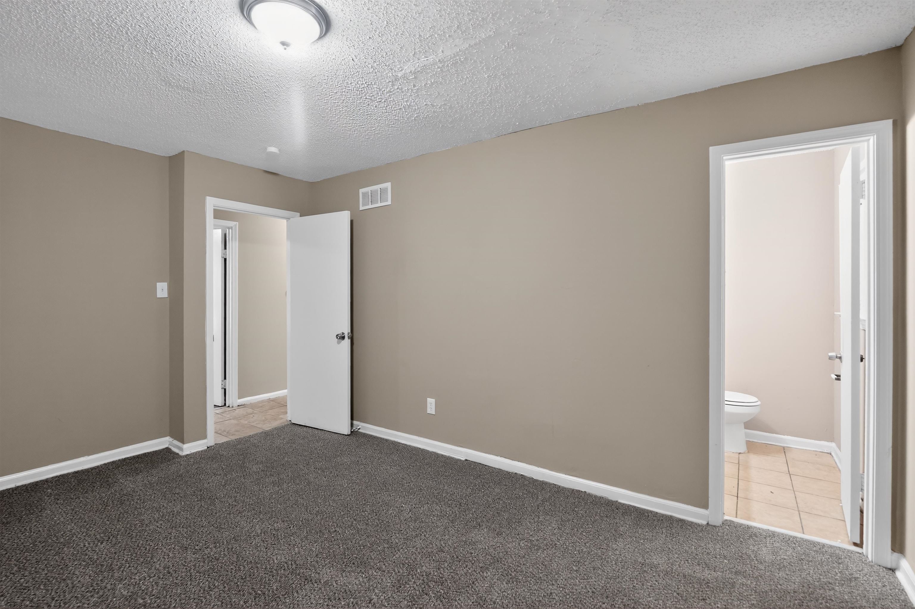 3608 Cane Ridge Drive Memphis, TN 38109 - Photo 24 of 31 Neutral-toned interior room featuring dark gray carpet flooring, white baseboards, and a flush mount ceiling light fixture