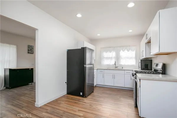 a kitchen with granite countertop appliances a sink cabinets and a wooden floor