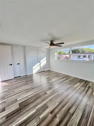 a view of empty room with wooden floor and fan