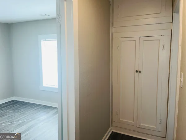 a view of an empty room with wooden floor and closet