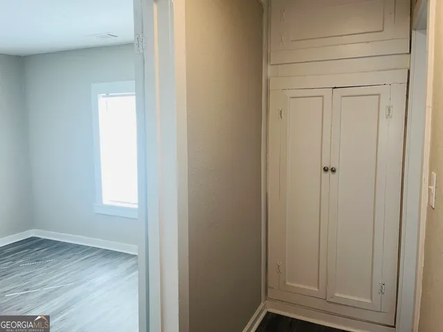 a view of an empty room with wooden floor and closet
