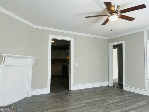 an empty room with wooden floor and ceiling fan