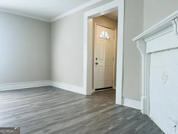 a view of an empty room with closet and wooden floor