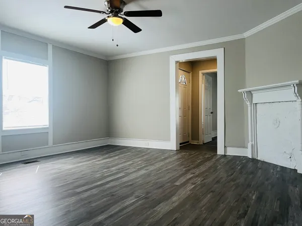 a view of empty room with wooden floor and fan