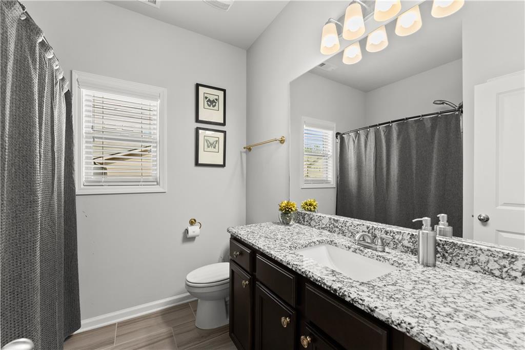 527 Gadwall Circle Jefferson, GA 30549 - Photo 25 of 42 a bathroom with a granite countertop sink a toilet and a mirror