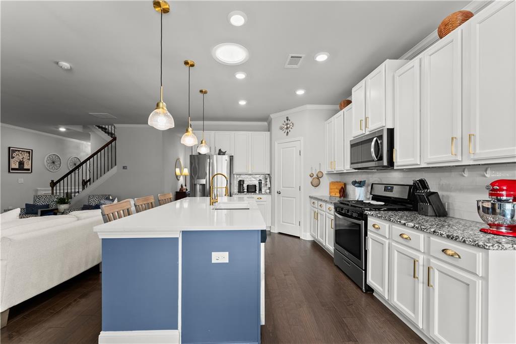 527 Gadwall Circle Jefferson, GA 30549 - Photo 6 of 42 a large kitchen with stainless steel appliances kitchen island granite countertop a sink a stove and a wooden floors