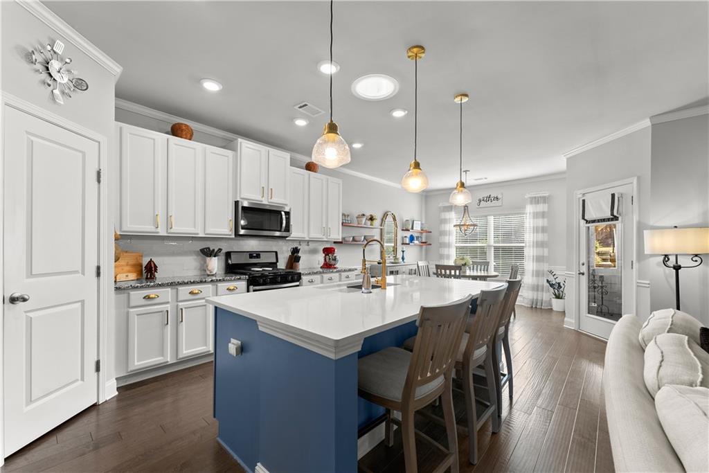 527 Gadwall Circle Jefferson, GA 30549 - Photo 7 of 42 a kitchen with stainless steel appliances kitchen island granite countertop a sink dishwasher a stove a refrigerator a dining table and chairs with wooden floor