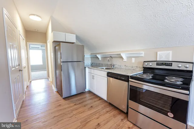 a kitchen with a refrigerator stove and wooden floor