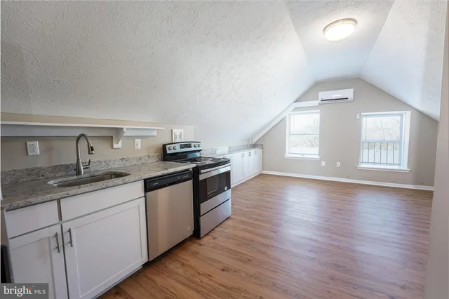a kitchen with granite countertop a sink cabinets and wooden floor
